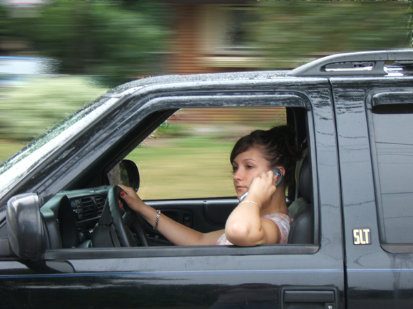 Teen girl uses mobile phone while driving